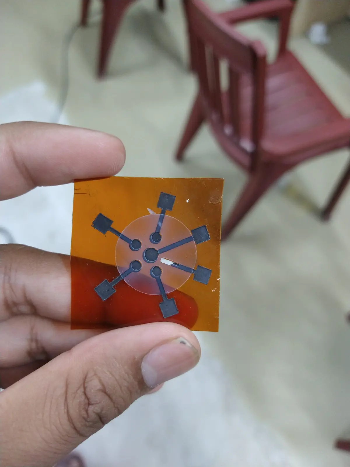 A multiplexed sensor on Kapton: seven screen-printed electrodes radiating from a centre well, with an SLA-printed chamber bonded over it.